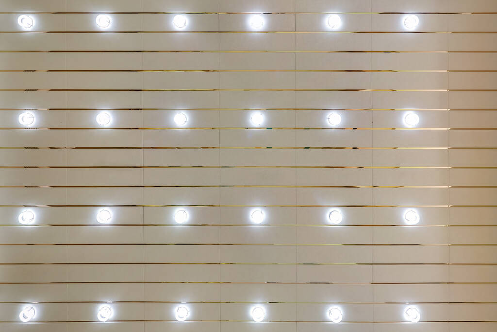 rytmická textura na zavěšeném stropě s řadami halogenových žárovek a konstrukce ze sádrokartonu s lustrem. Roztáhnout strop bílý a složitý tvar. - Fotografie, Obrázek