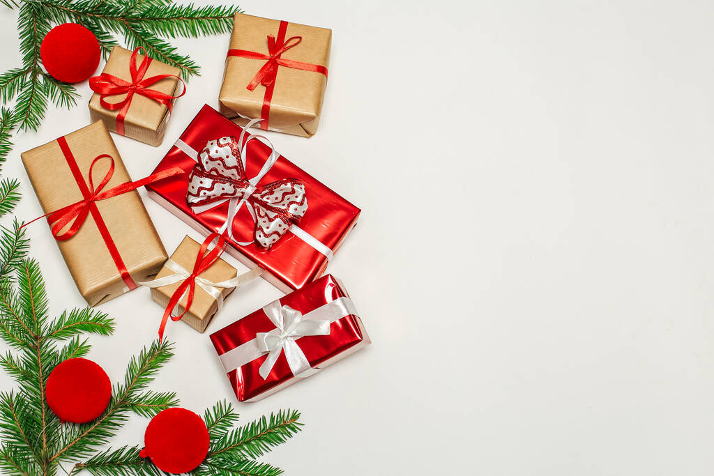 Composition de Noël, branches de sapin avec cadeaux, décorations rouges sur une surface blanche verticale, espace pour le texte - Photo, image