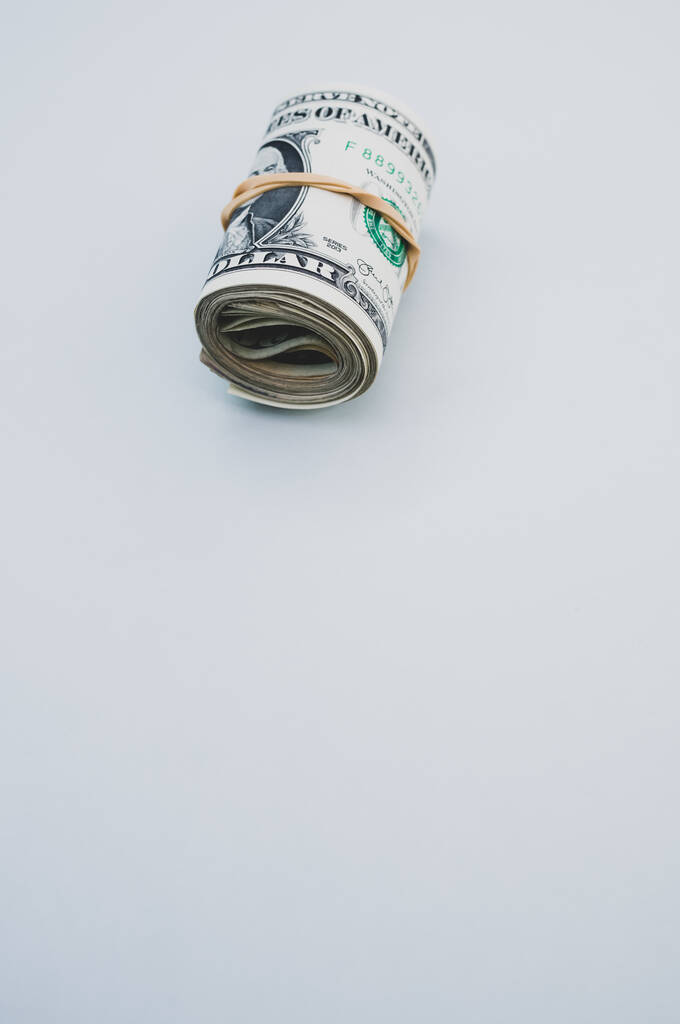Een verticaal shot van opgerolde dollarbiljetten op een blauw oppervlak - Foto, afbeelding