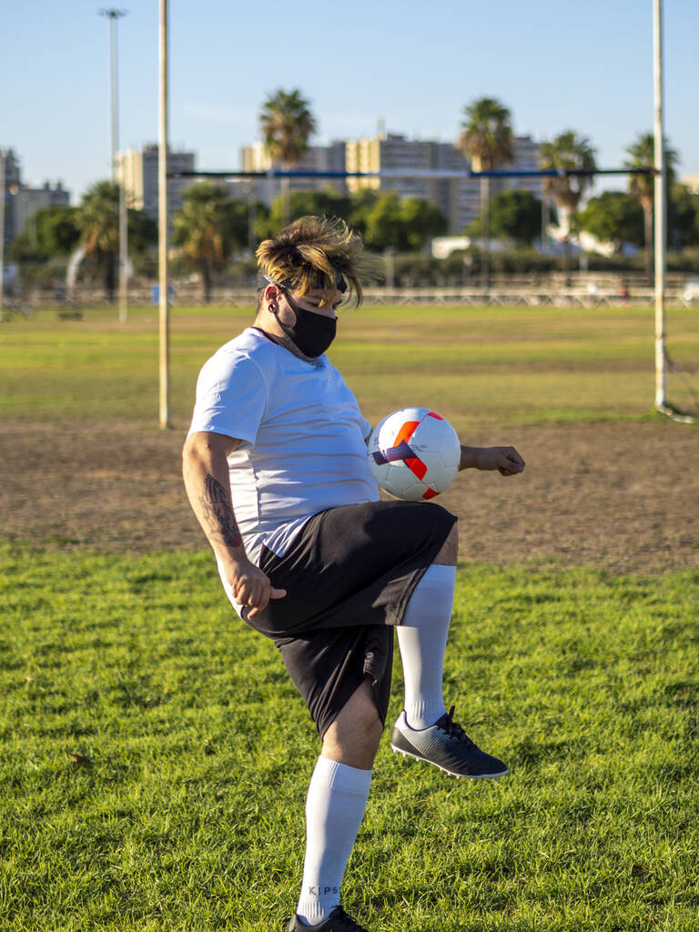 Futbolista w białej koszuli żonglujący piłką na boisku. - Zdjęcie, obraz