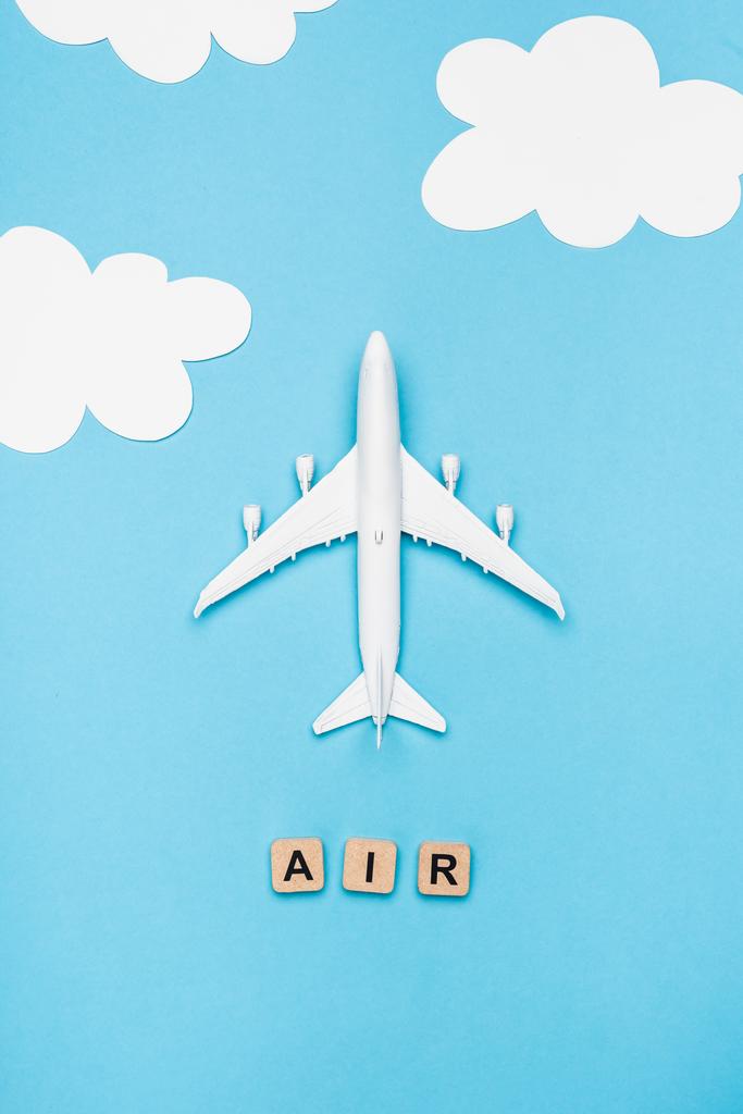 Draufsicht auf Flugzeugmodell und Würfel mit Wortluft auf blauem Himmelshintergrund - Foto, Bild