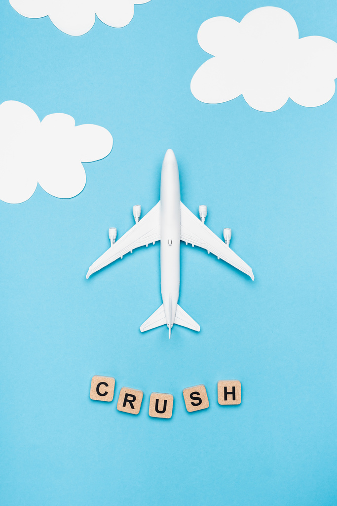 top view of plane model and cubes with word crush on blue sky background - Photo, Image