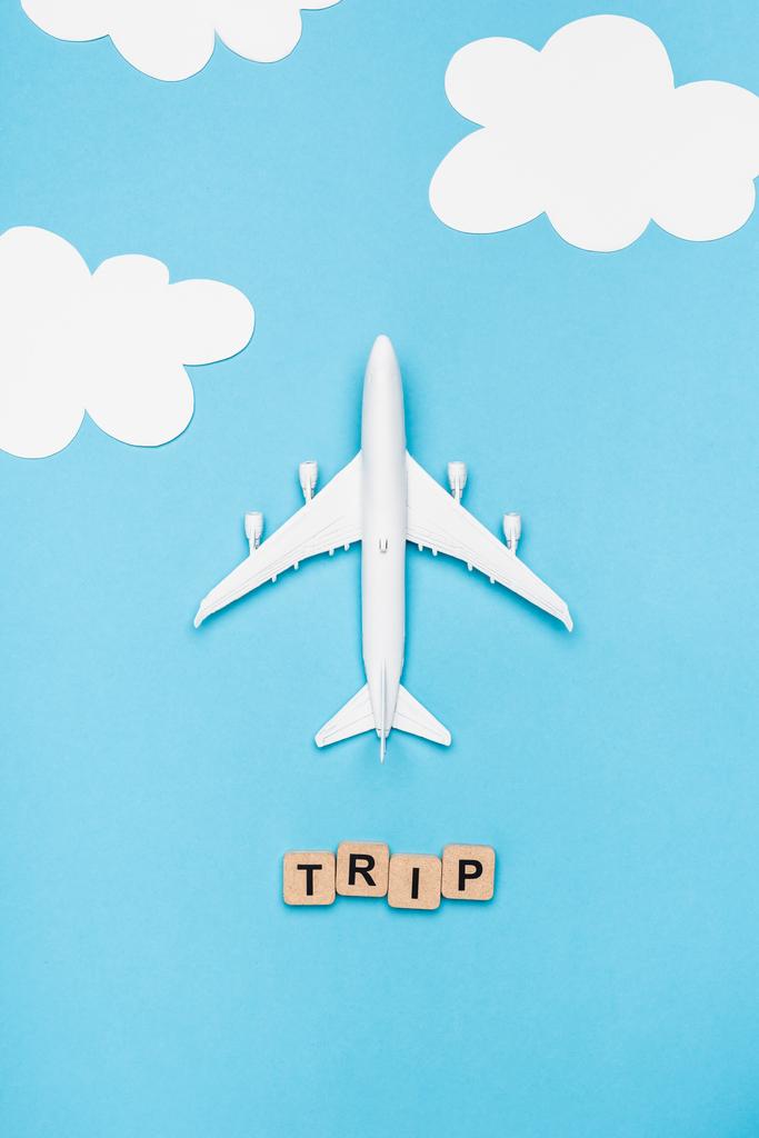 vrchní pohled na letadlo model a kostky s slovo výlet na modrém pozadí oblohy - Fotografie, Obrázek