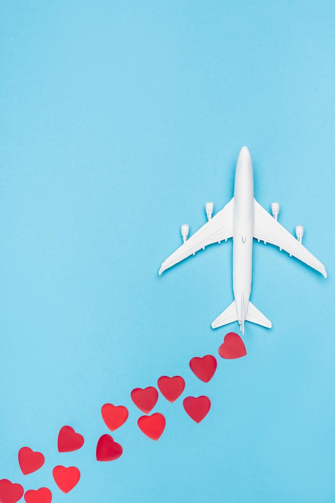 Draufsicht auf Flugzeugmodell und rote Herzen auf blauem Hintergrund - Foto, Bild