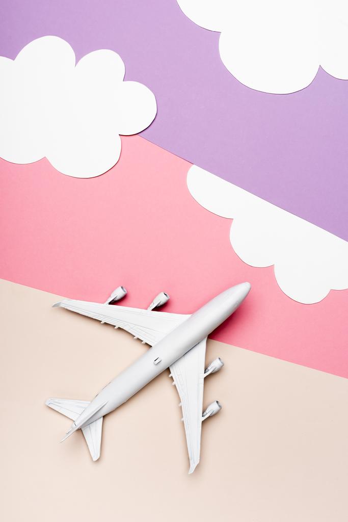 雲のあるカラフルな背景に白い飛行機のモデルのトップビュー - 写真・画像