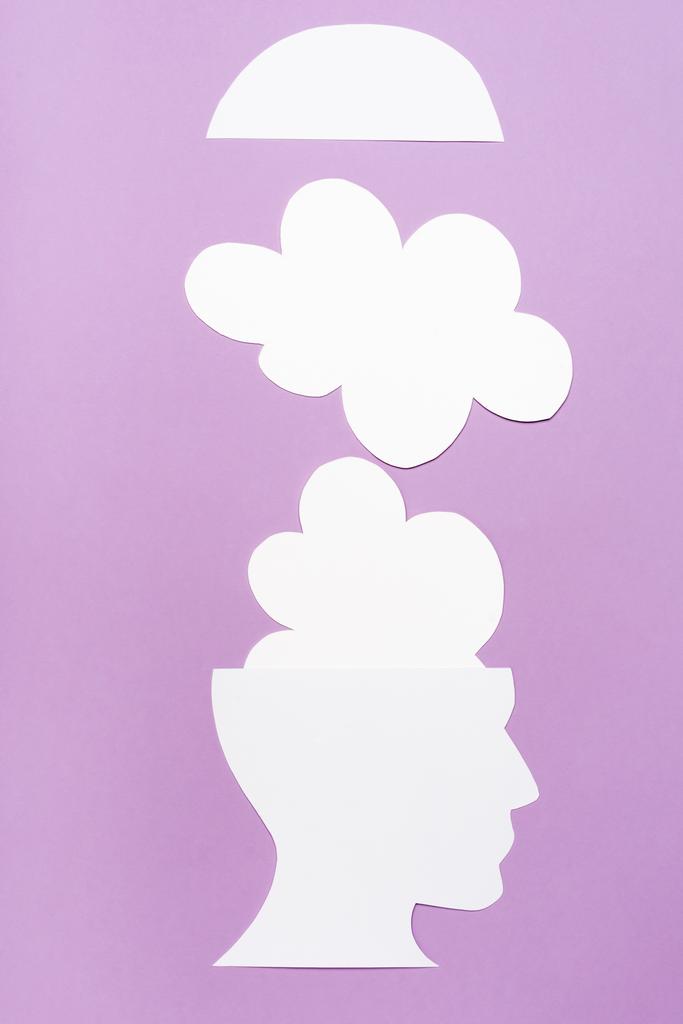 vista superior de la cabeza humana de papel y nubes sobre fondo violeta - Foto, Imagen