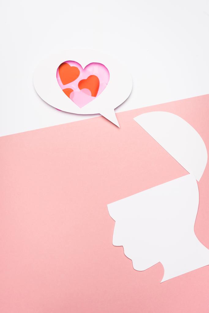 felső nézet beszéd buborék szívvel és emberi fejjel fehér és rózsaszín háttér - Fotó, kép