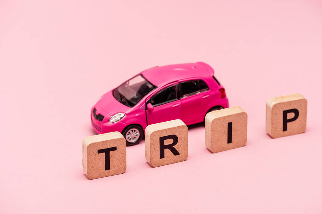 автомобиль и слово поездки на кубиках на розовом фоне - Фото, изображение