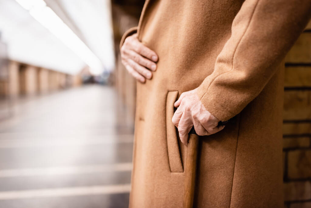 częściowy widok starszego mężczyzny w płaszczu stojącym z laską na stacji metra - Zdjęcie, obraz