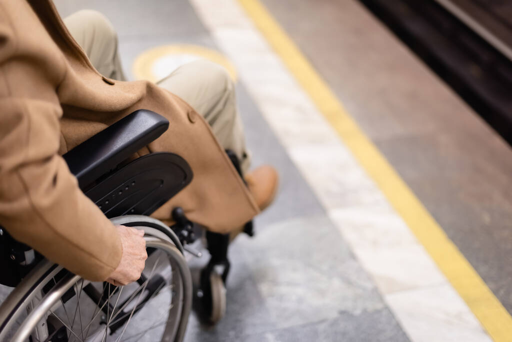 bijgesneden beeld van wazig gehandicapte man in rolstoel op metroperron - Foto, afbeelding