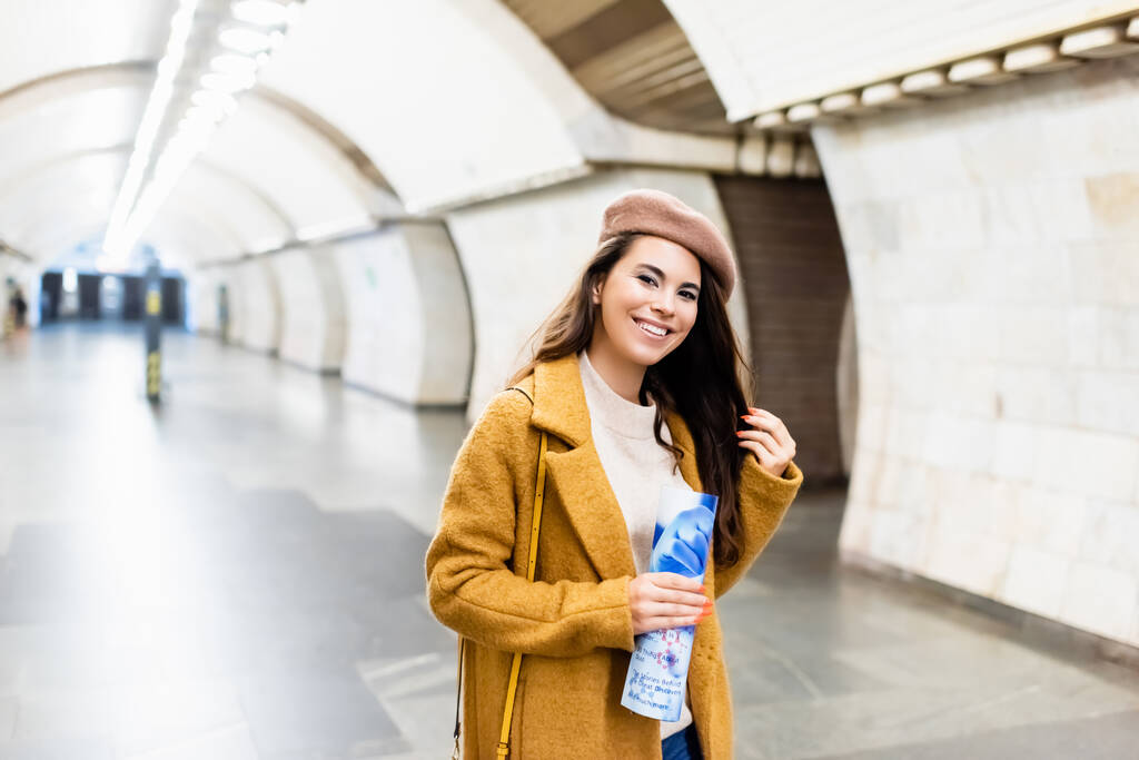 fröhliche Frau im stylischen Herbst-Outfit mit Magazin am U-Bahnhof - Foto, Bild