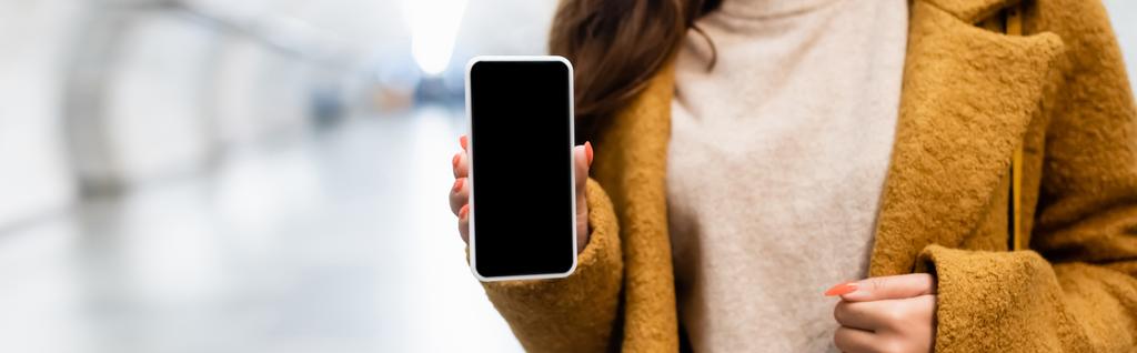 Güz ceketli bir kadının elinde beyaz ekranlı akıllı telefon ve afiş vardı. - Fotoğraf, Görsel