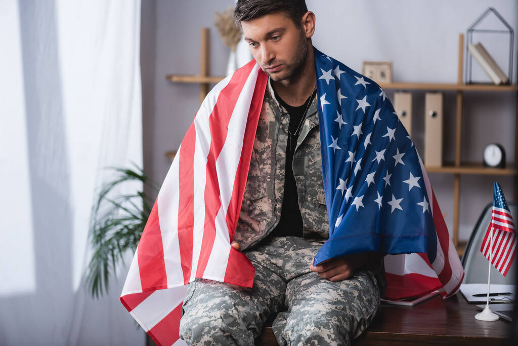 Amerikan bayrağına sarılmış üzgün bir asker. - Fotoğraf, Görsel