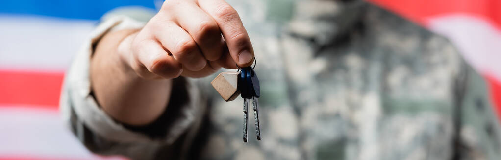 partial view of patriotic military man holding keys near american flag on blurred background - Photo, Image