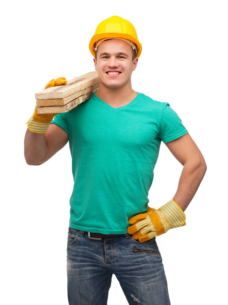 glimlachend arbeider in helm met houten planken - Foto, afbeelding