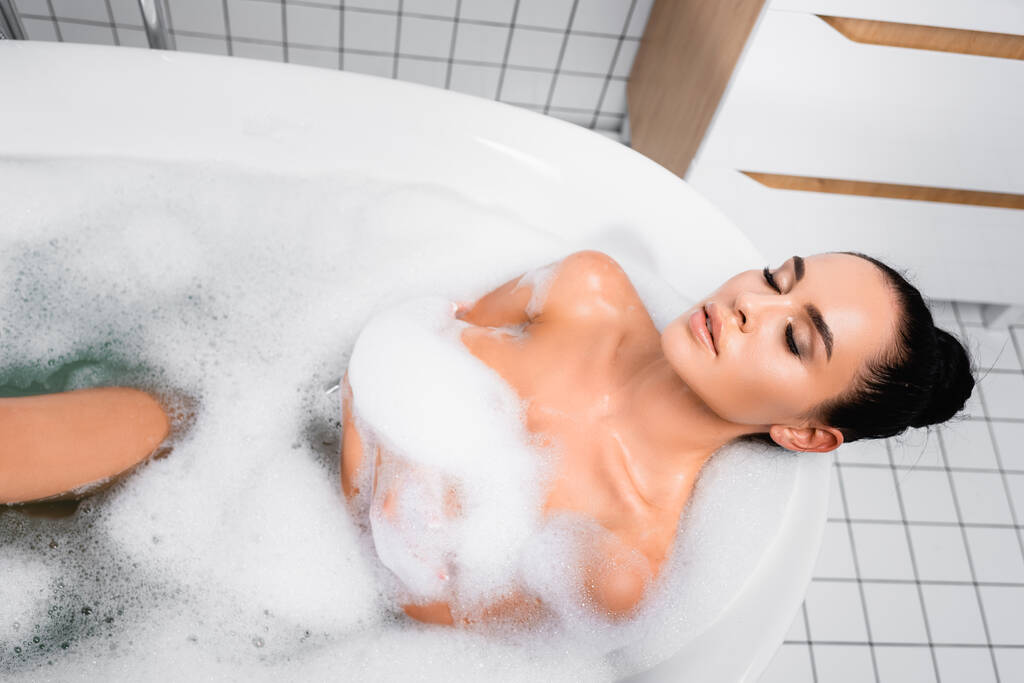 Brunette vrouw neemt bad met zepen thuis  - Foto, afbeelding