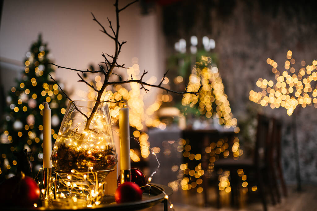 Año Nuevo 2021 interior con velas, bombillas y bokeh. Habitación decorada para la celebración de Navidad. Árbol de Navidad con regalos - Foto, Imagen