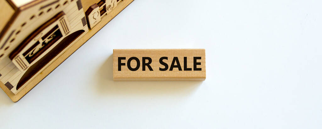 Wooden block with words 'for sale' near miniature house. Beautiful white background, copy space. Business concept. - Photo, Image