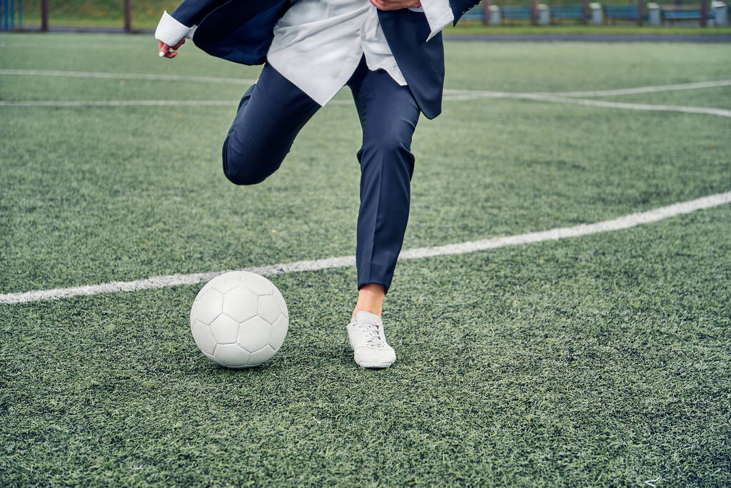 Όμορφη νεαρή κοπέλα με κοστούμι γραφείου παίζει ποδόσφαιρο - Φωτογραφία, εικόνα