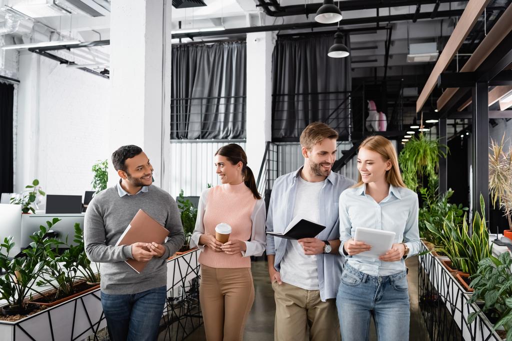 Empresários multiétnicos sorridentes com café para ho e tablet digital andando no escritório  - Foto, Imagem