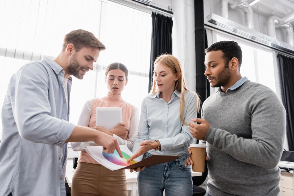 Νέοι πολυεθνικοί επιχειρηματίες με καφέ και ψηφιακή ταμπλέτα που δείχνουν πολύχρωμα δείγματα στο γραφείο  - Φωτογραφία, εικόνα