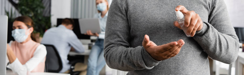 Vágott kilátás üzletember használ kézfertőtlenítő közelében kollégák orvosi maszkok elmosódott háttér, banner  - Fotó, kép