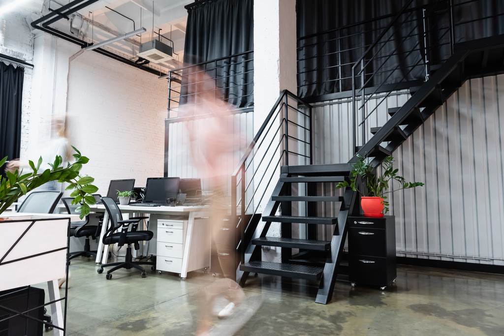 Размытие движения бизнесвумен, идущих рядом с компьютерами в офисе  - Фото, изображение