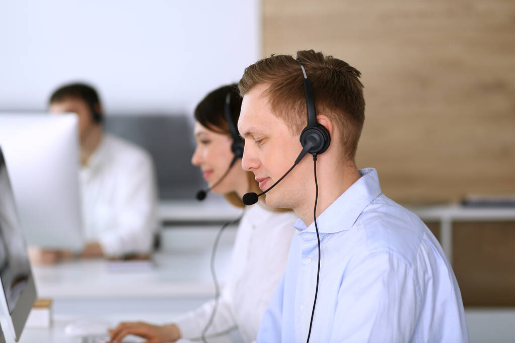 Call center. Group of diverse operators at work. Focus on businessman in headset at customer service office. Business concept - Photo, Image