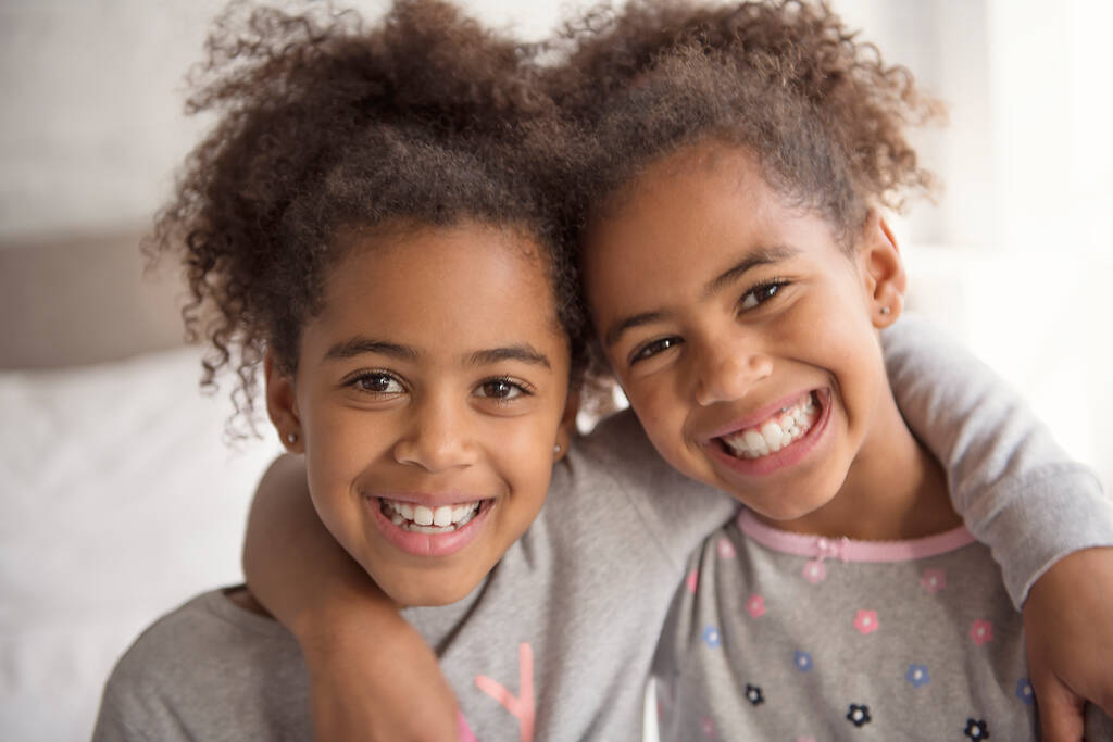 Дві маленькі афроамериканські дівчини на ліжку. - Фото, зображення