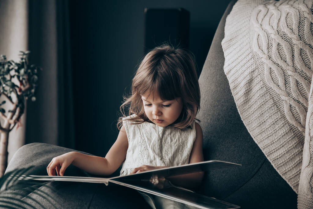 家で本を読んでいる赤ん坊の少女。隔離中に隔離されてる - 写真・画像