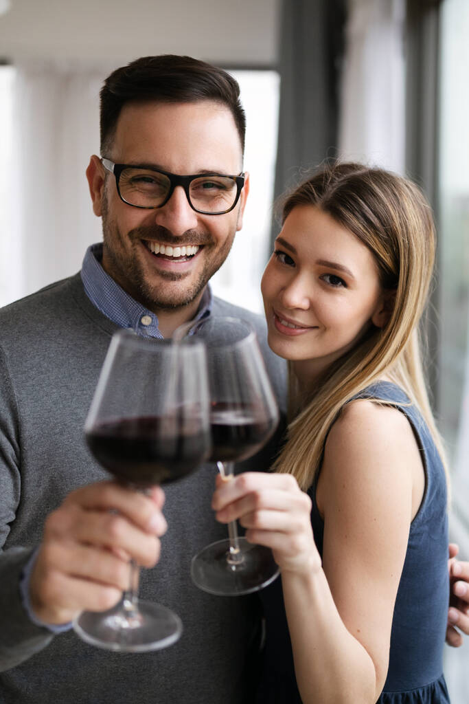 Feliz hermosa pareja enamorada abrazando y bebiendo vino tinto en casa - Foto, Imagen