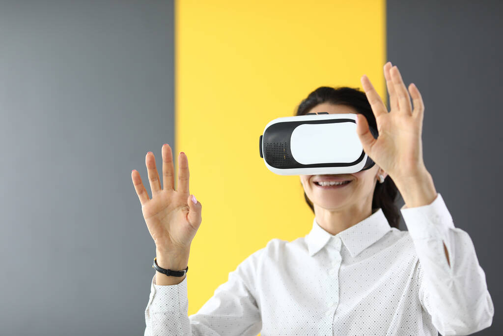 Donna in piedi in occhiali di realtà virtuale e tiene le mani in alto - Foto, immagini