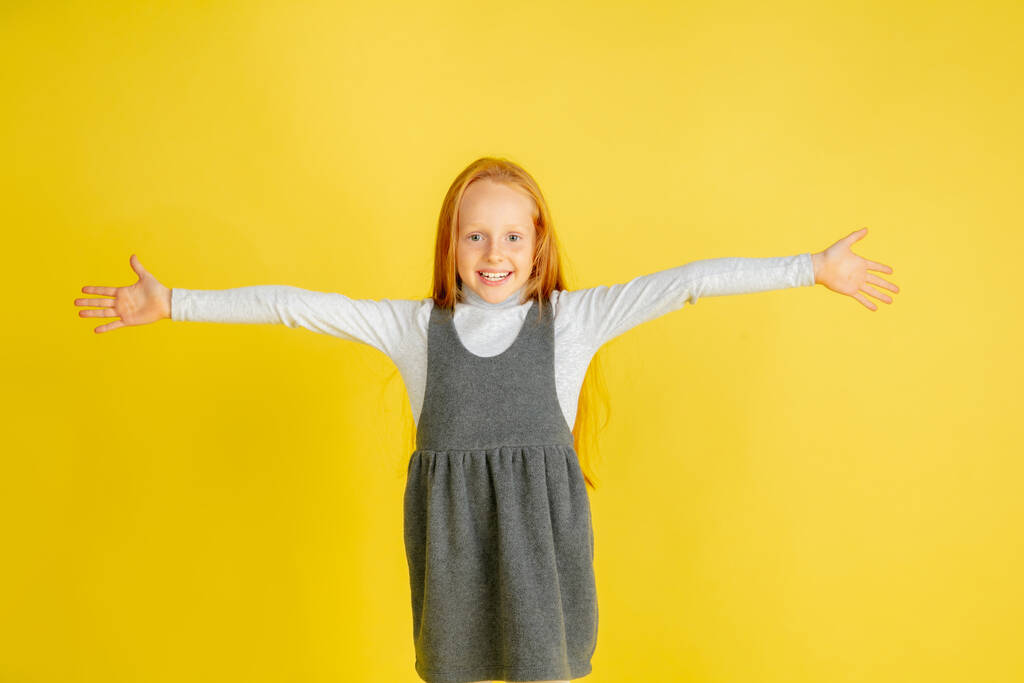 Portret małej białej dziewczynki z jasnymi emocjami odizolowanej na żółtym tle studia - Zdjęcie, obraz