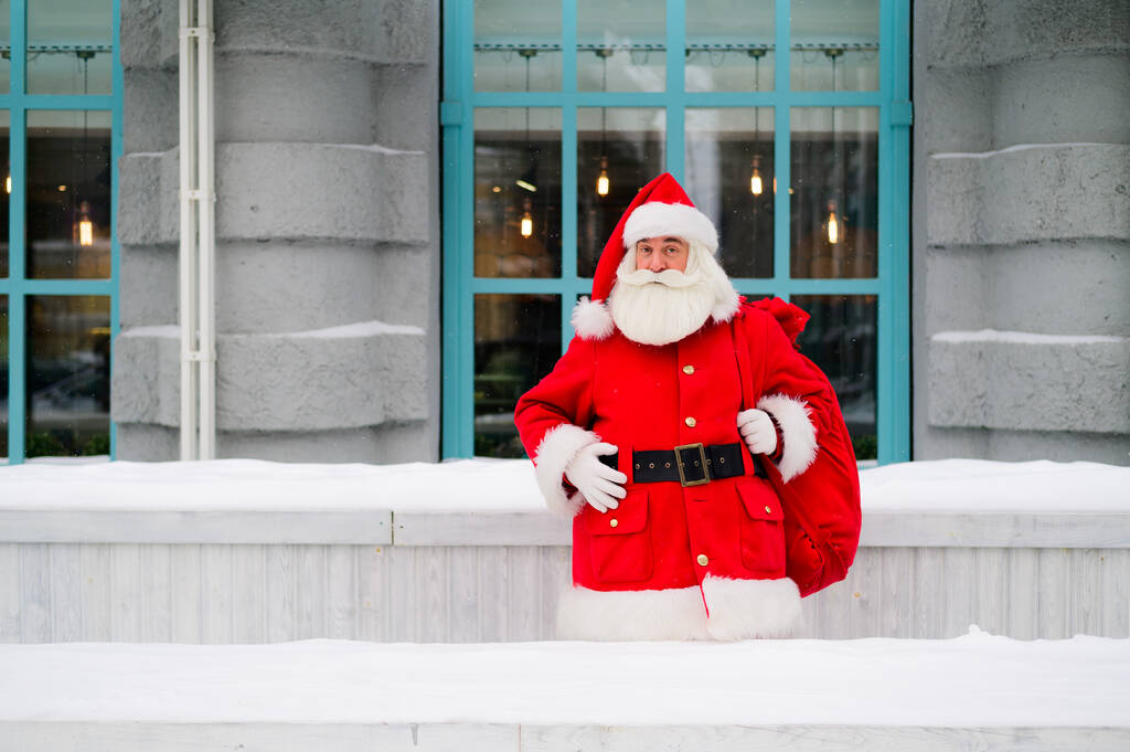 Der Weihnachtsmann lehnt im Winter an der Fassade eines Hauses - Foto, Bild