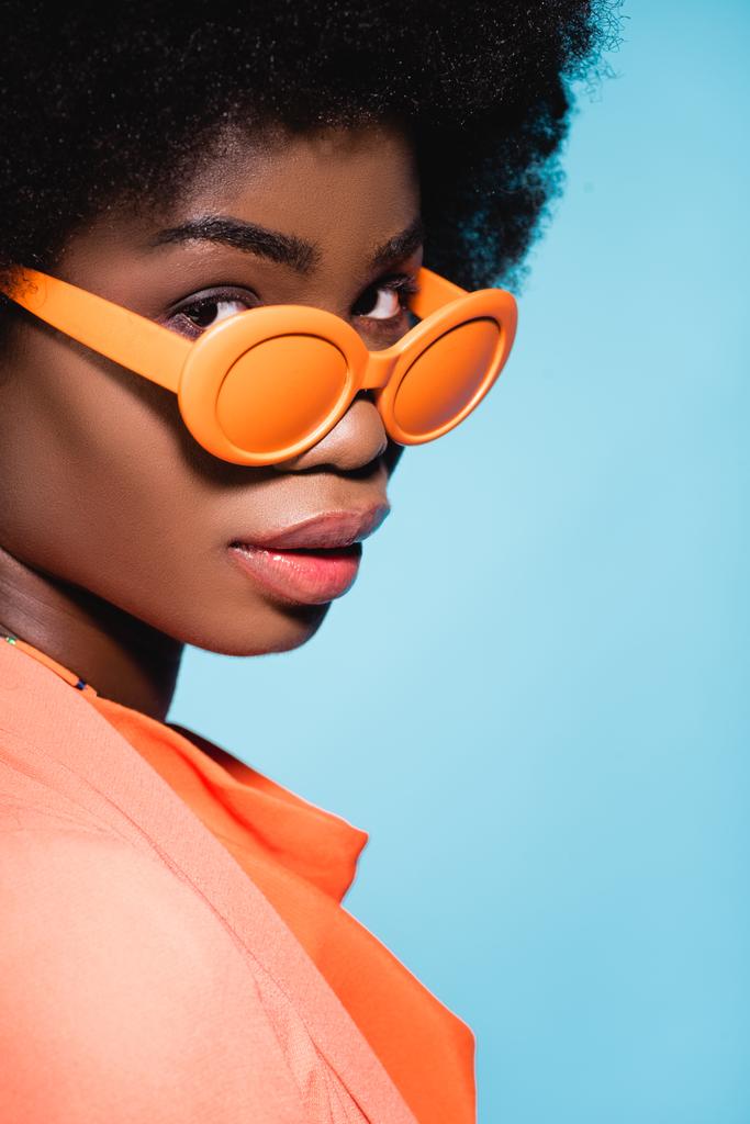 afro-américaine jeune femme en tenue élégante orange isolé sur fond bleu - Photo, image