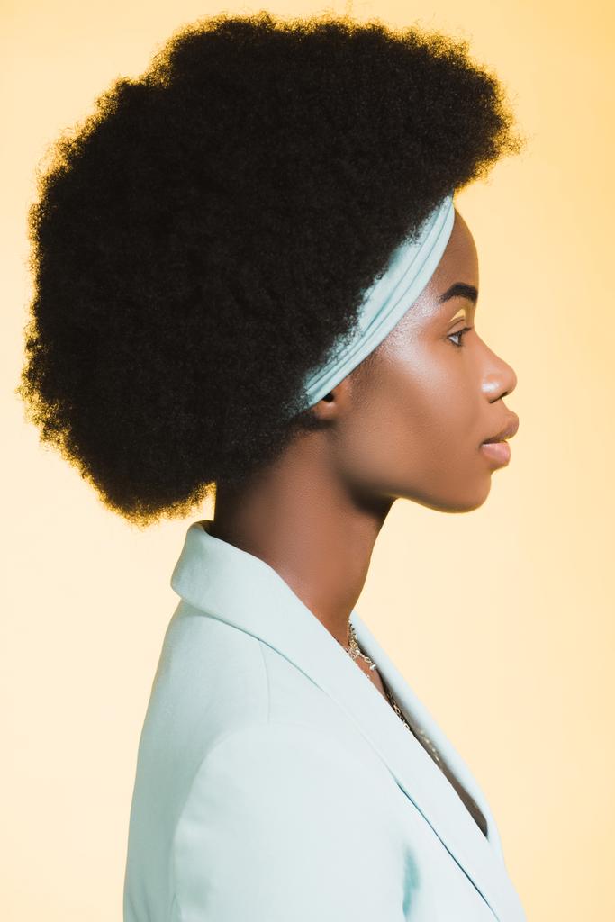 Profil afrykańskiej młodej kobiety w niebieskim stylowym stroju odizolowanej na żółto  - Zdjęcie, obraz