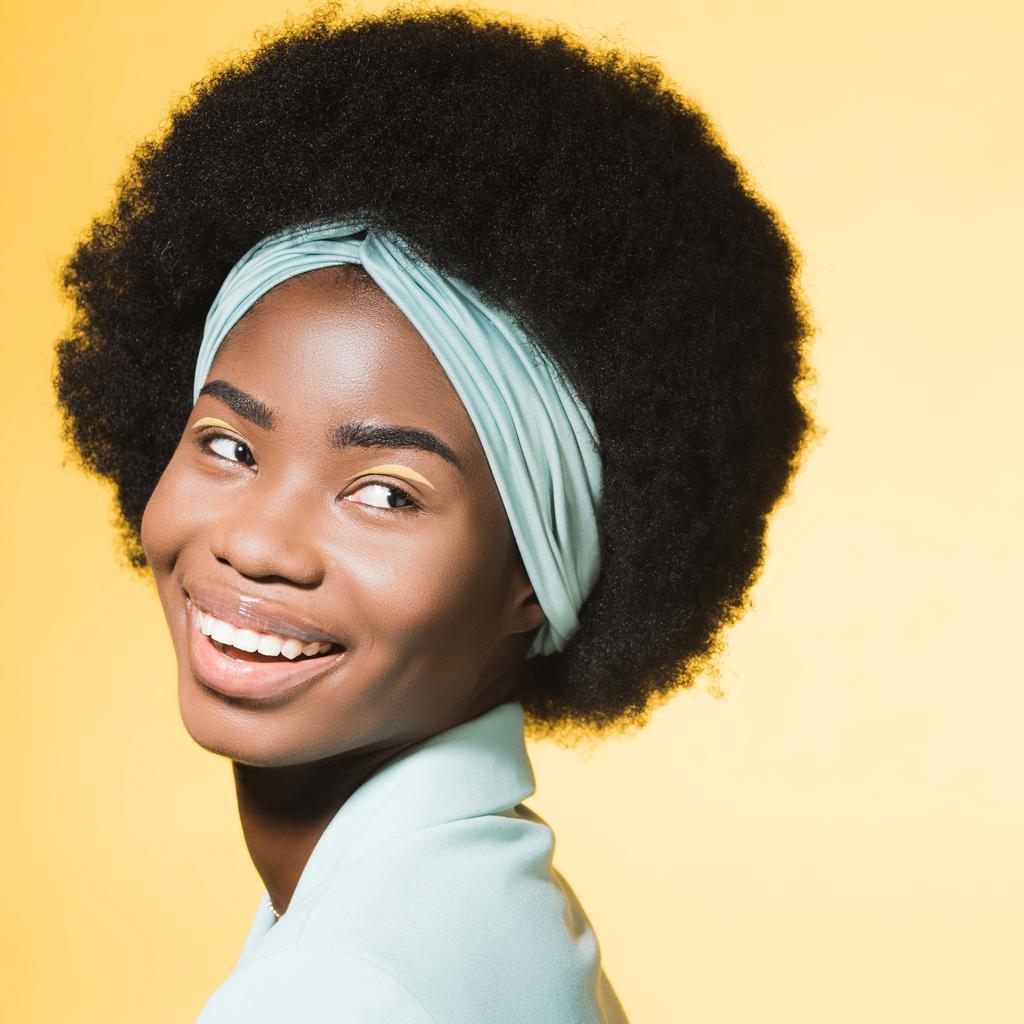 onnellinen afrikkalainen amerikkalainen nuori nainen sininen tyylikäs asu eristetty keltainen  - Valokuva, kuva