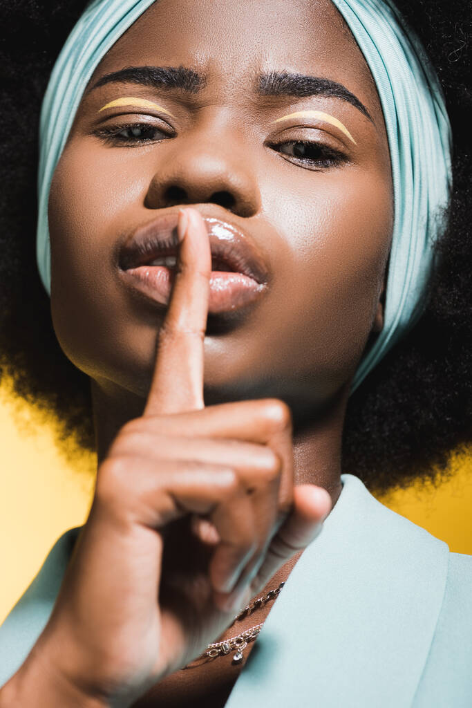african american young woman in blue stylish outfit showing shh isolated on yellow  - Photo, Image