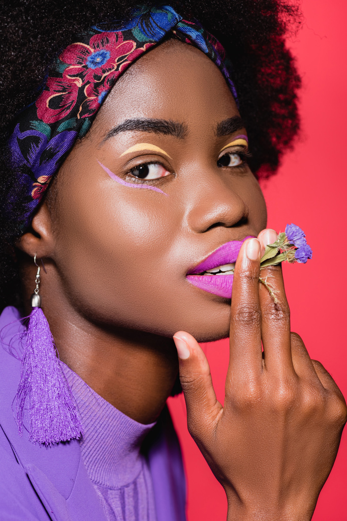 african american young woman in purple stylish outfit smoking flower isolated on red - Photo, Image