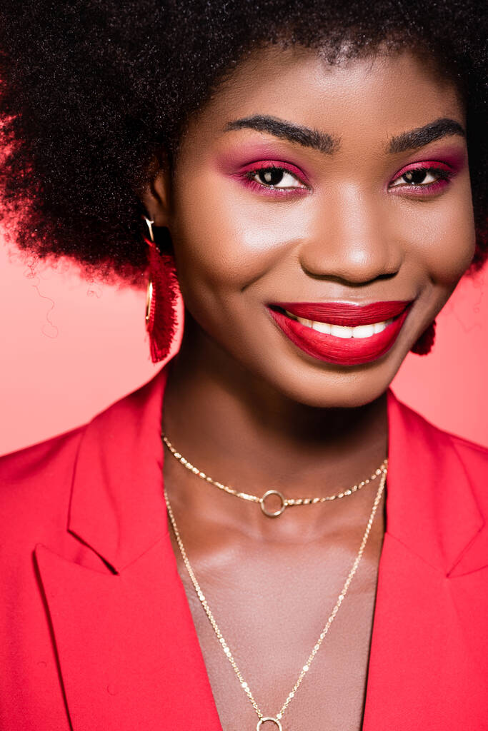 smiling african american young woman in stylish outfit isolated on red - Photo, Image