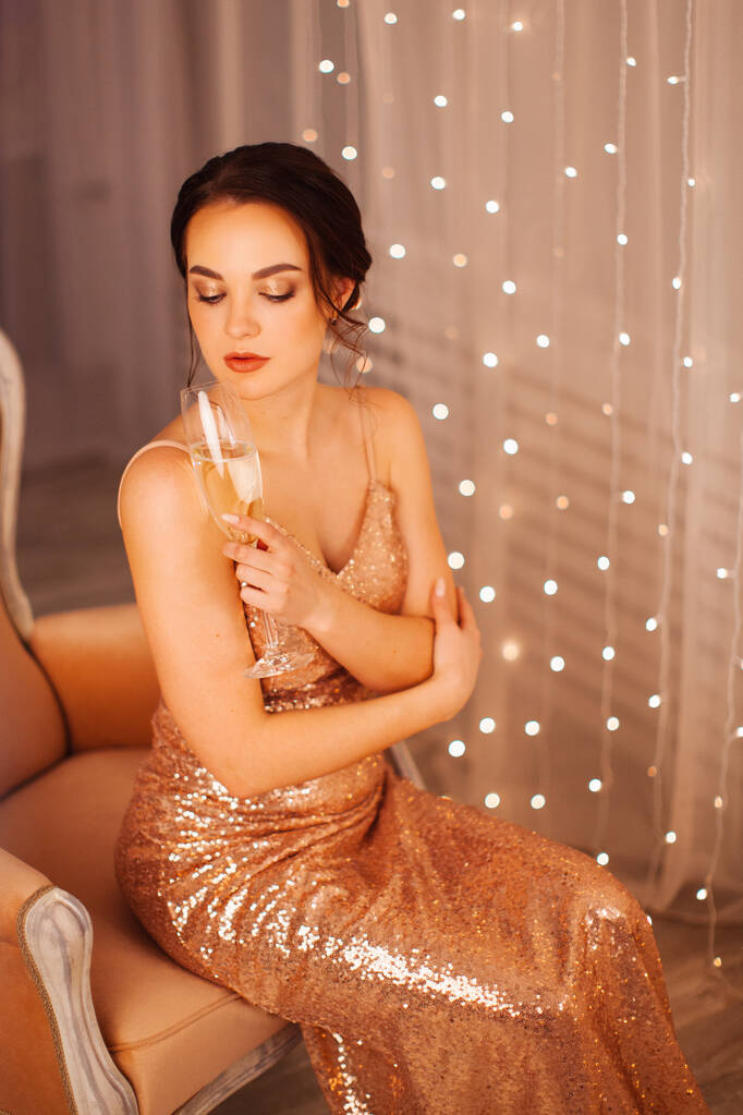 Κορίτσι με βραδινό φόρεμα ποζάρει στο στούντιο της Πρωτοχρονιάς με ένα ποτήρι σαμπάνια - Φωτογραφία, εικόνα