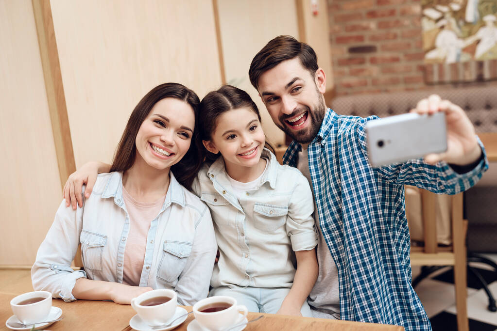 Jovem família feliz tomando selfie na cafetaria. - Foto, Imagem