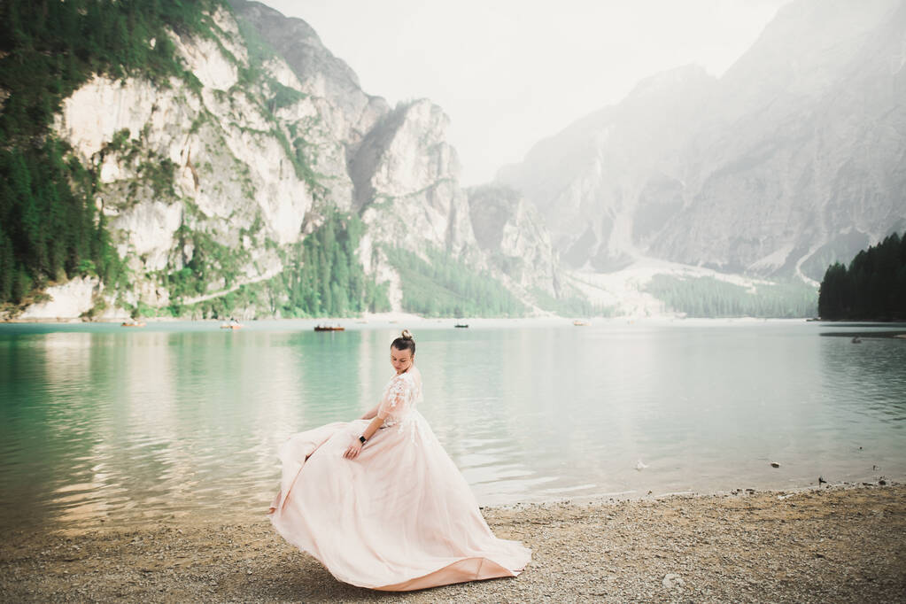 Bela noiva posando perto de rochas contra fundo as montanhas
 - Foto, Imagem