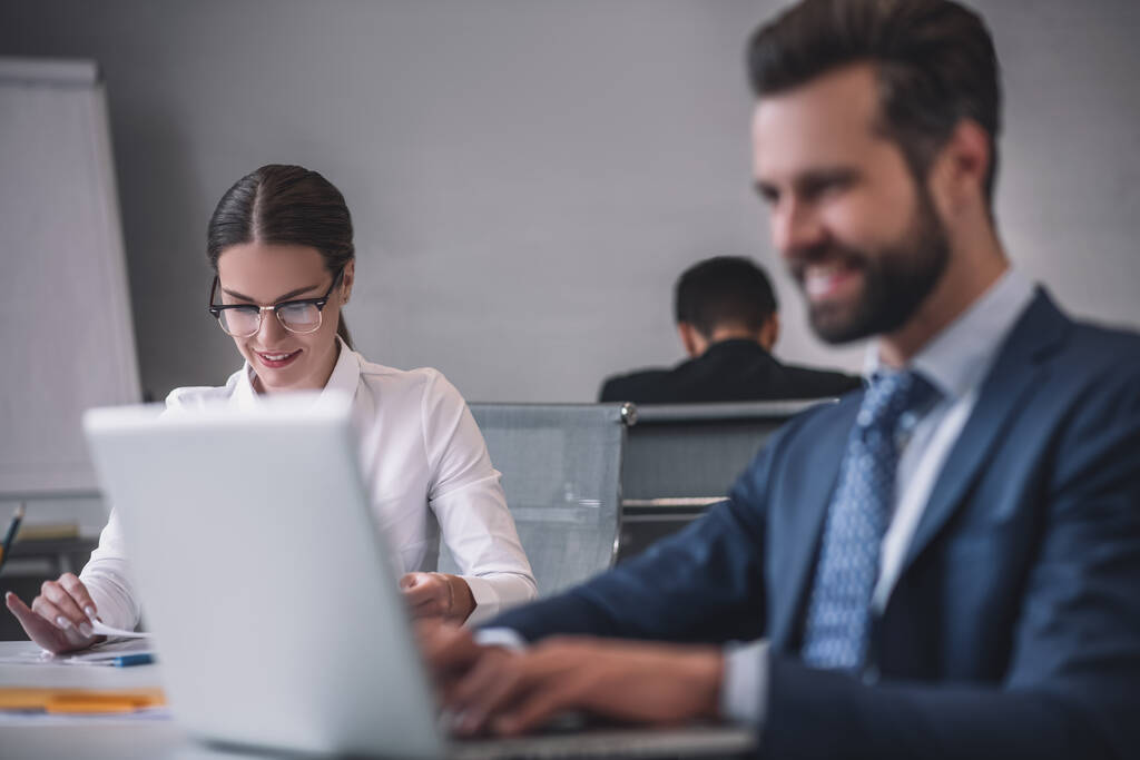 Smiling woman and man behind laptop in office - Photo, Image