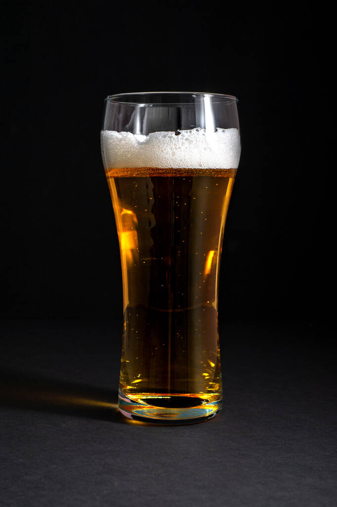  frisches Bier in einem schönen hohen Glas auf schwarzem Hintergrund - Foto, Bild