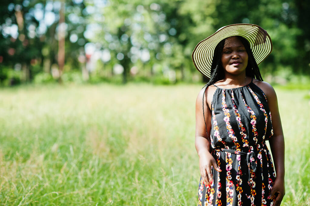 Portrait of gorgeous african american woman 20s in summer hat posing at green grass in park. - Photo, Image