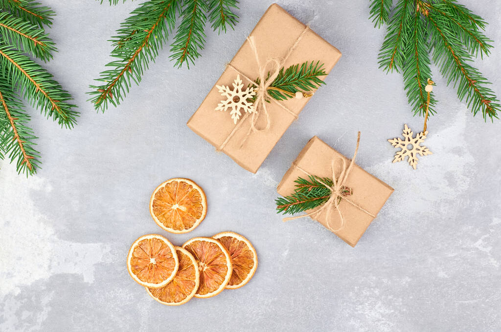 Weihnachtsgeschenkboxen mit trockenen Orangenscheiben und grünen Tannenzweigen - Foto, Bild