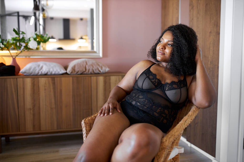 mujer africana guapa con cuerpo semidesnudo más tamaño se sienta en el sillón - Foto, Imagen