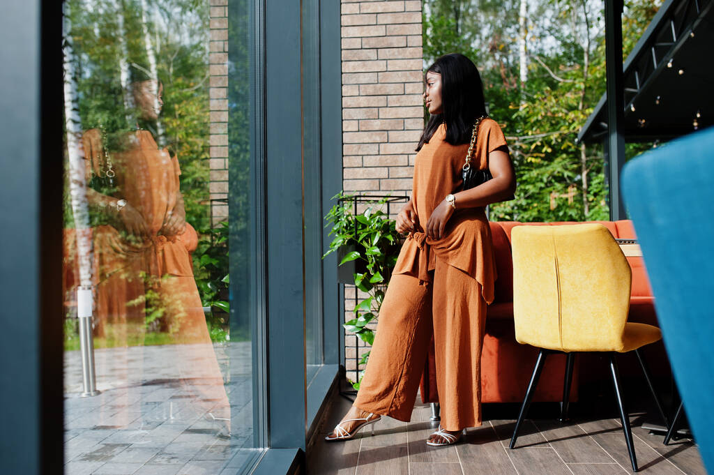 Retrato de belleza joven mujer negra, llevar traje naranja, posar en el restaurante. - Foto, imagen
