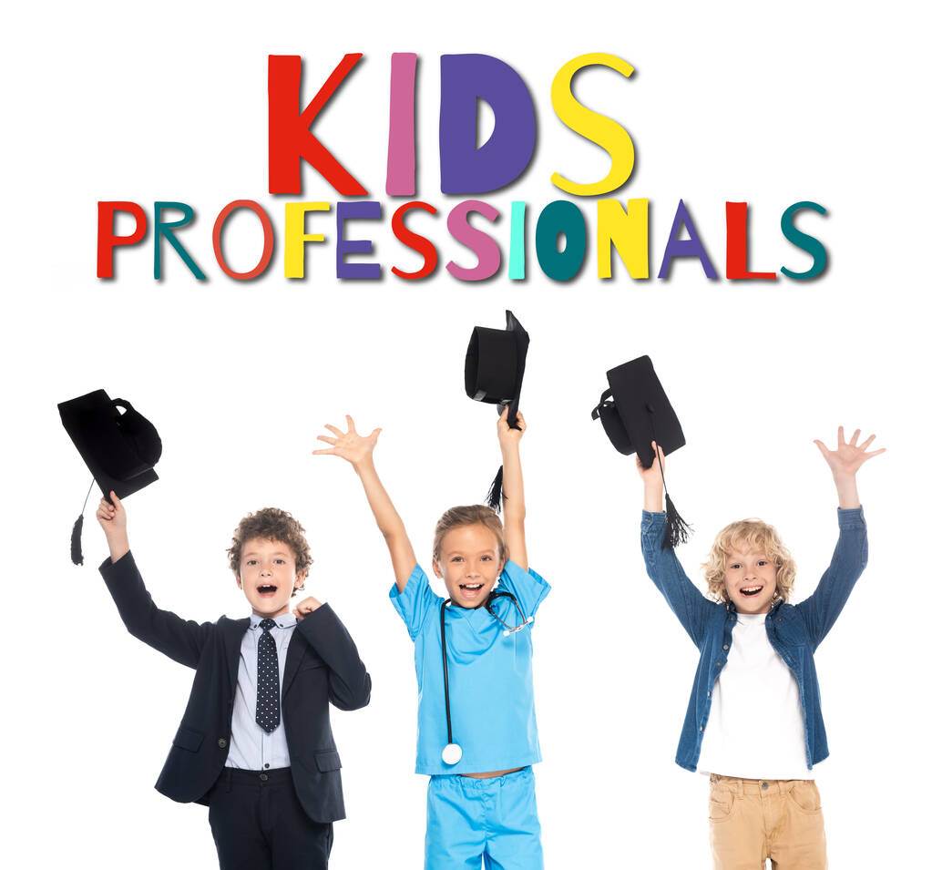 bambini eccitati vestiti in costumi di diverse professioni che tengono berretti neri sopra le teste vicino ai bambini professionisti lettering su bianco  - Foto, immagini